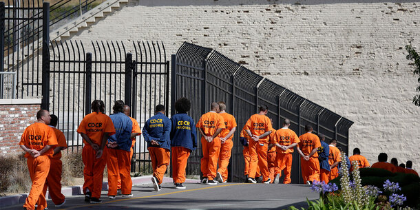people in orange jumpsuits walking into a prison