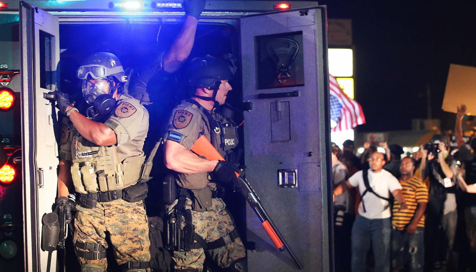 Heavily armed officers with military equipment exit a truck