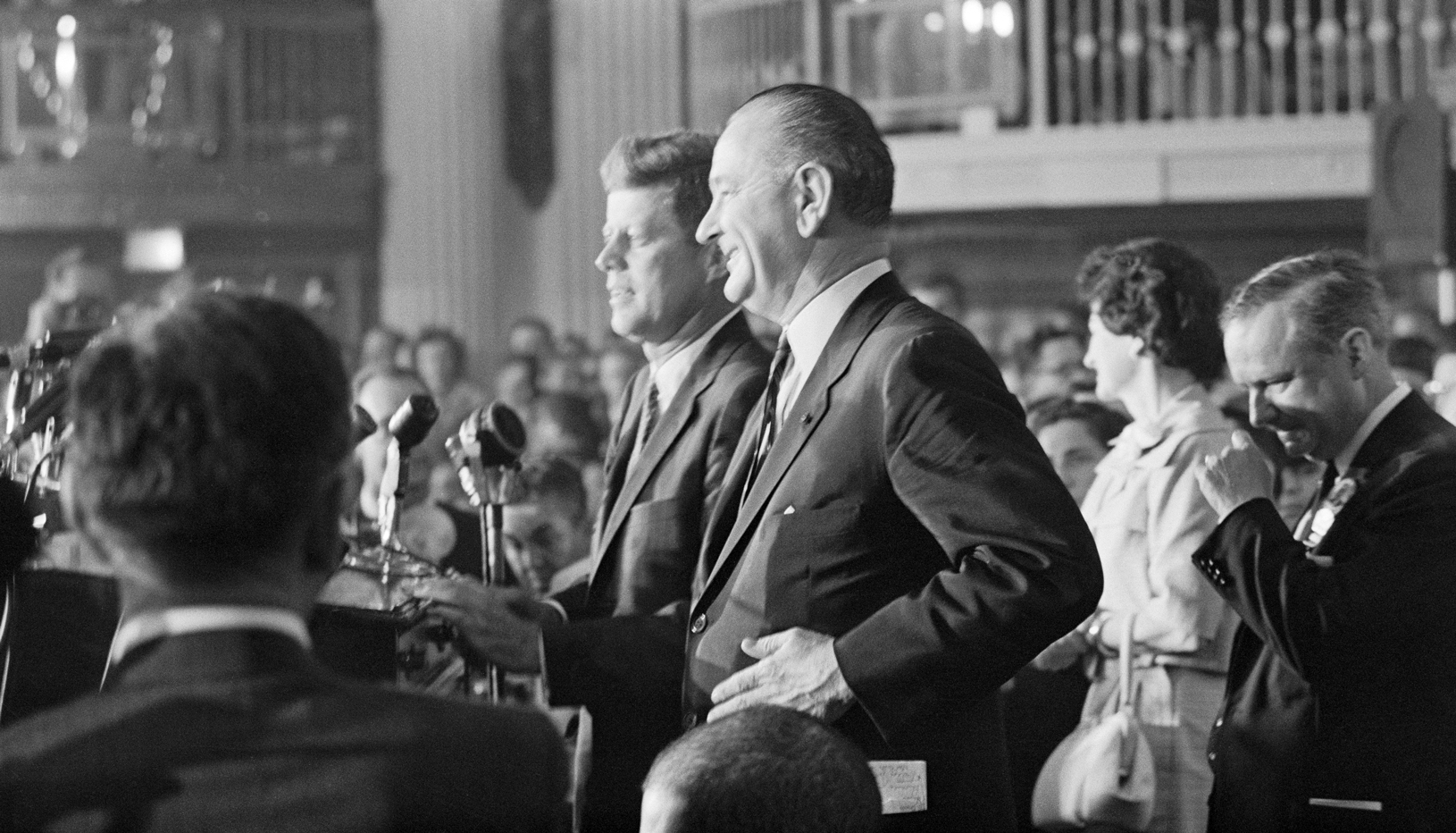 John F. Kennedy and Lyndon Johnson stand together at a podium.