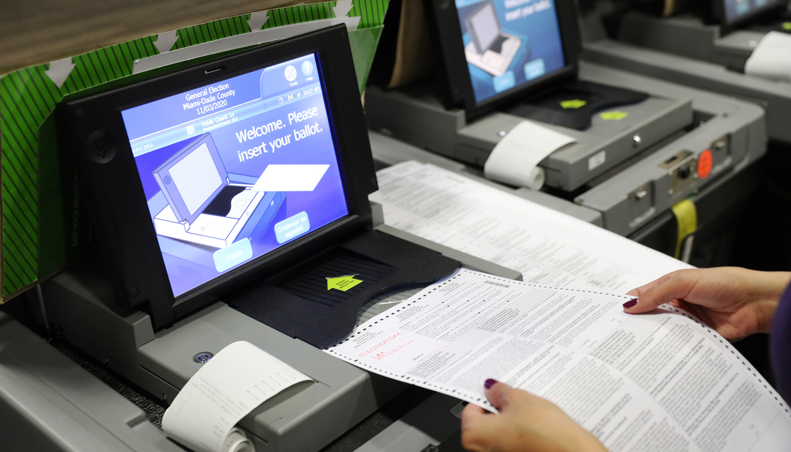 An election worker feeds a ballot into a scanner