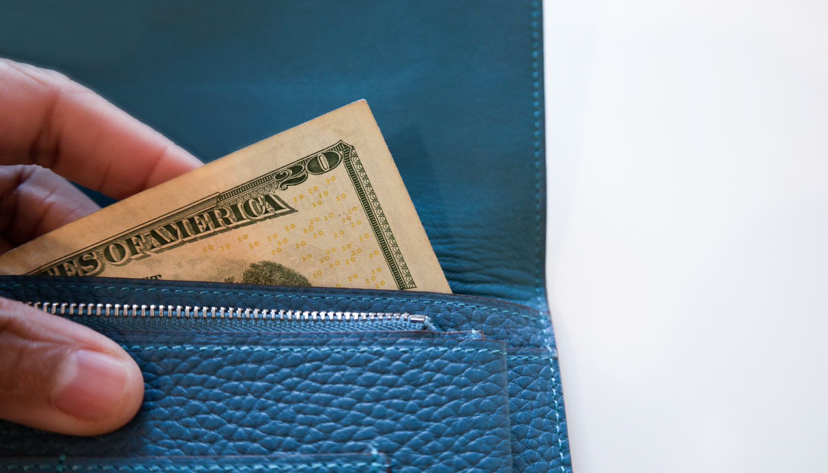 A close up shot of a 20 dollar bill bring taken out of a wallet