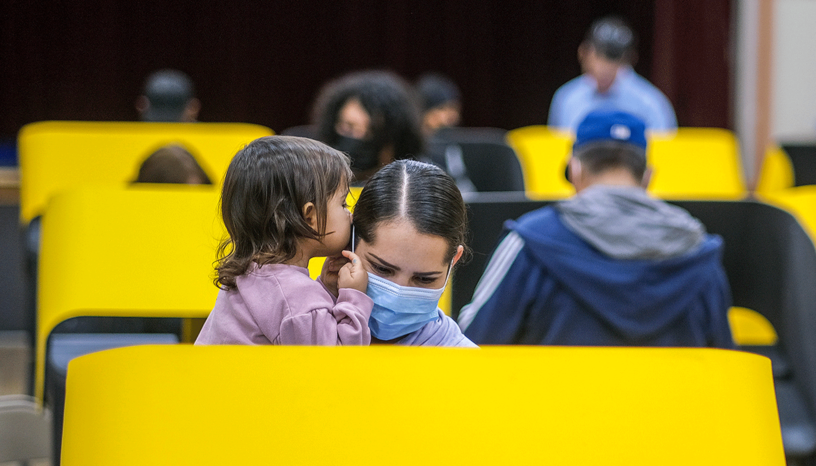 People voting at a yellow booth holding a child