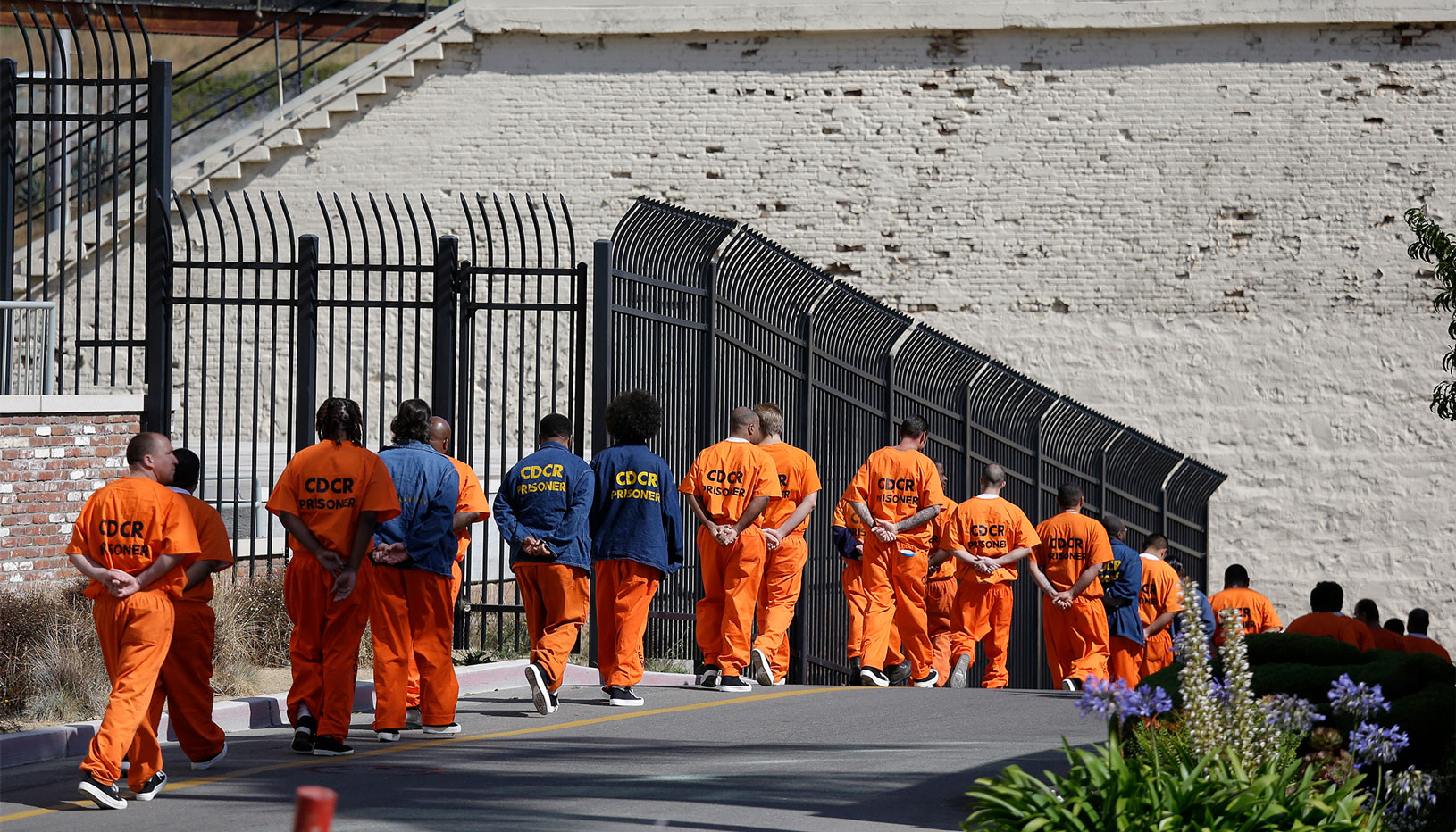 people in orange jumpsuits walking into a prison
