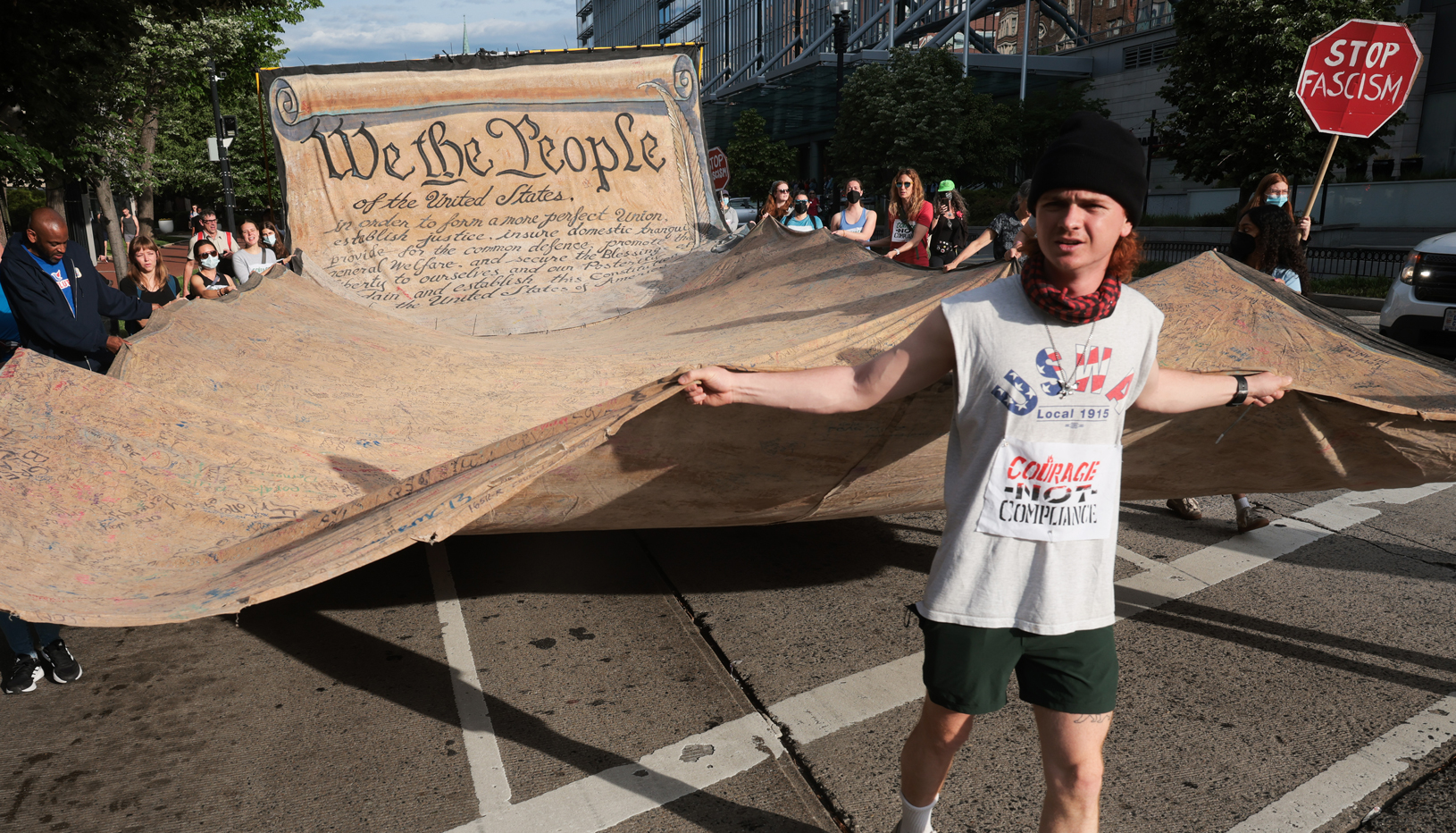 Photo of man carrying giant copy of the U.S. Constitution in demonstration. 