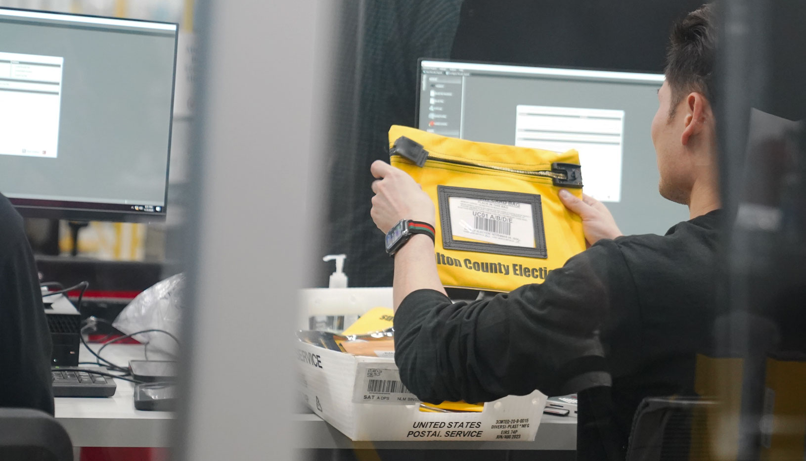 worker holding up yellow bag with Fulton County elections written on it