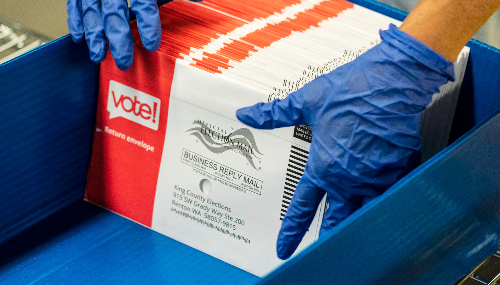 Gloved hands handling mail ballots