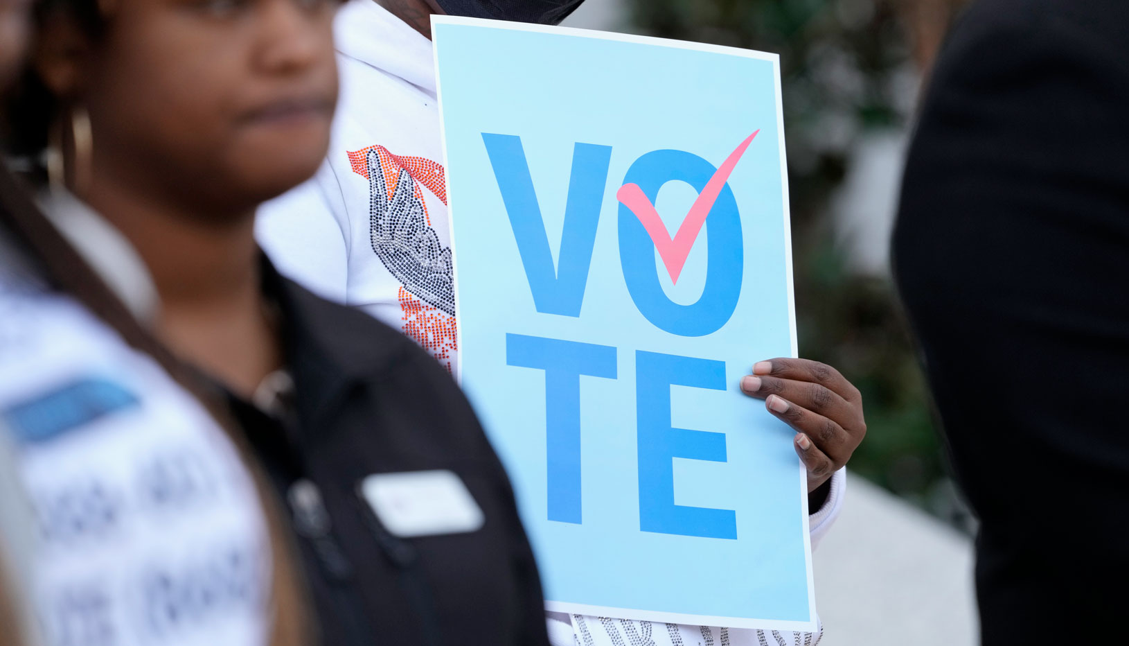 A voter standing next to a voting sign