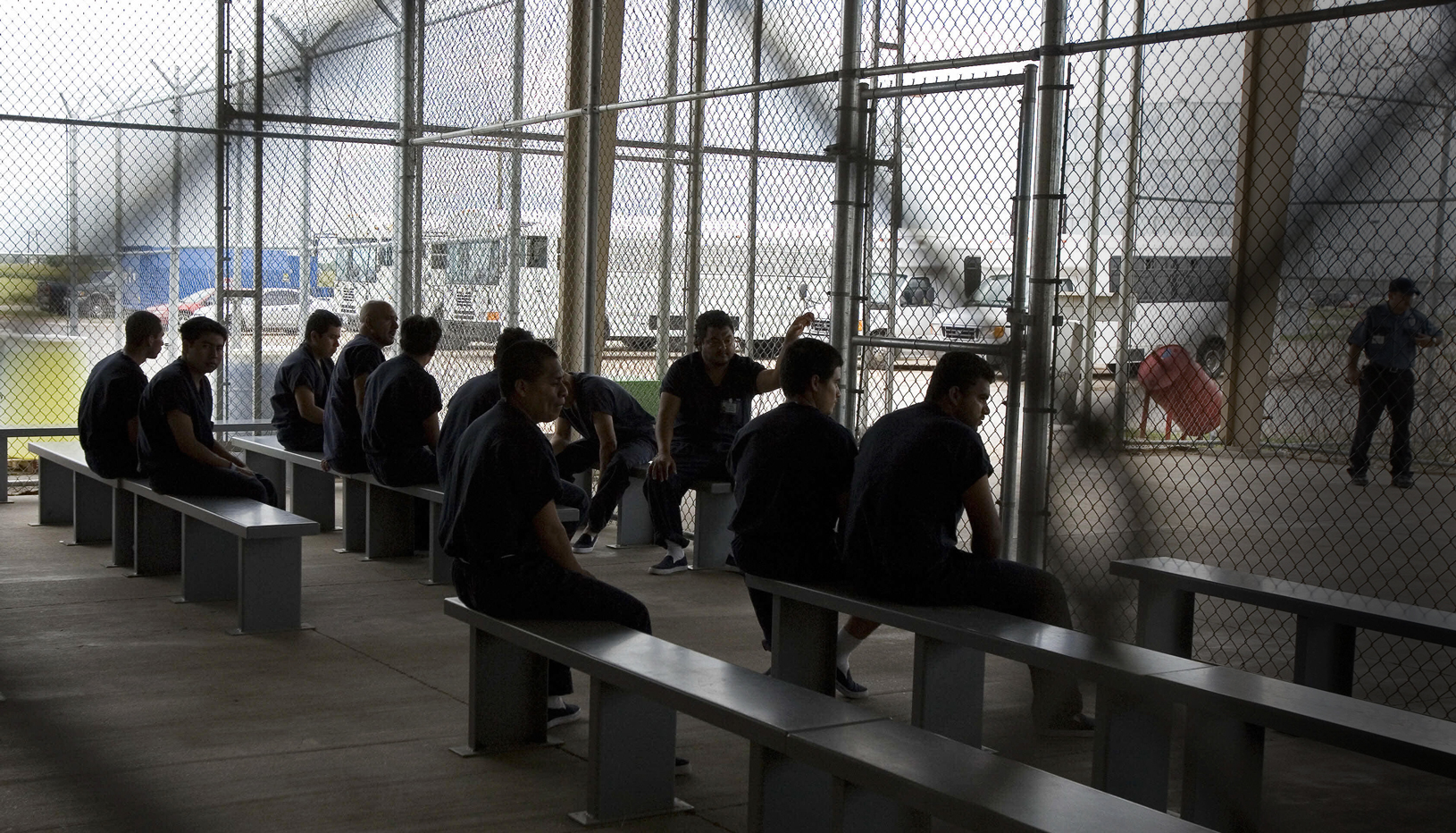 Men detained within a chain link fence