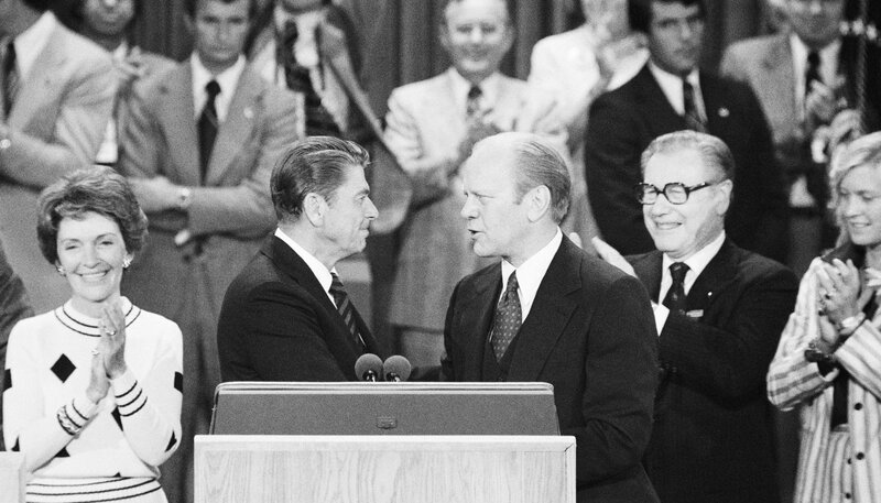Ronald Reagan and Gerald Ford shake hands at a podium