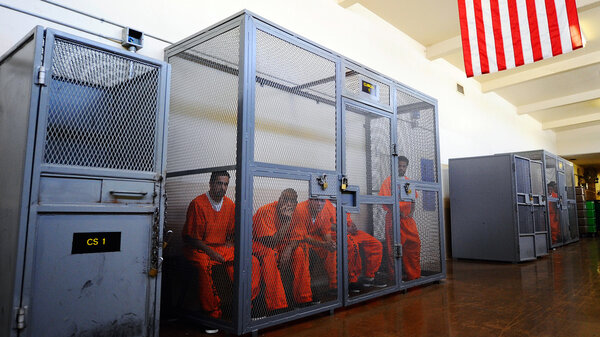 Incarcerated people locked in a cage.