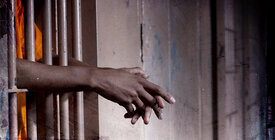 Hands stick out from behind prison bars