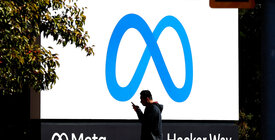 A man using his phone walks by Meta headquarters
