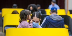 People voting at a yellow booth holding a child