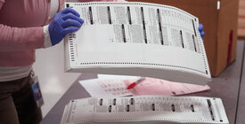 election official handling ballots with gloves