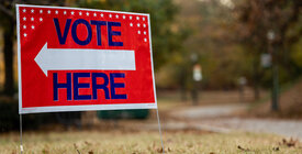 Red sign that has vote here text with white arrow