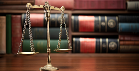 The scales of justice sit in front of legal books. 