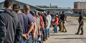 A group of men being apprehended by immigration agents