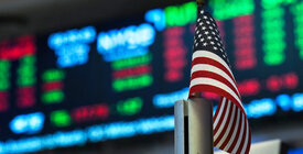 U.S. flag in front of a display of stock prices