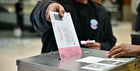 A mail ballot is dropped into a dropbox. 