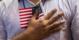 Man holding small American flag to chest