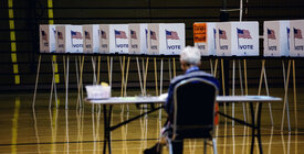 Worker in foreground, row of empty voting booths in background