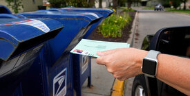 Mail ballot being dropped in mail slot
