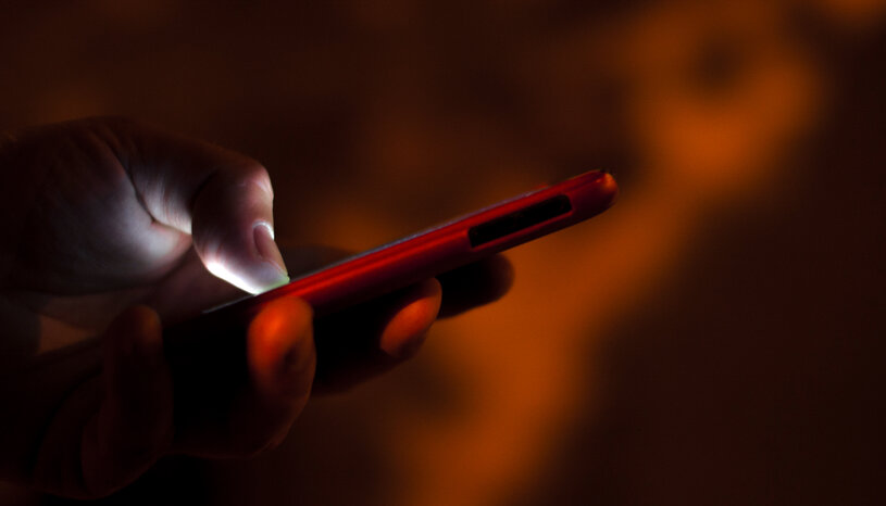 person holding cell phone on dark background