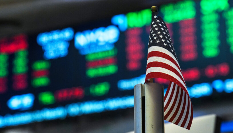 U.S. flag in front of a display of stock prices