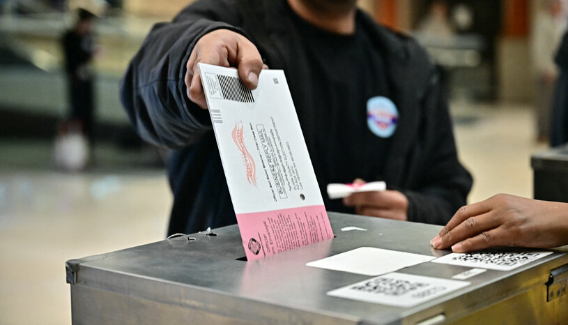 A mail ballot is dropped into a dropbox. 
