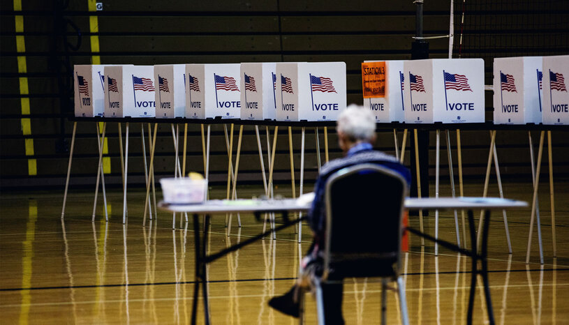 Worker in foreground, row of empty voting booths in background