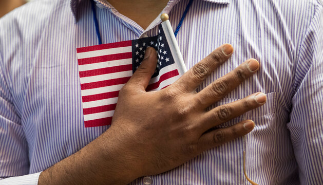 Man holding small American flag to chest
