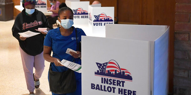 woman placing ballot in voting box.