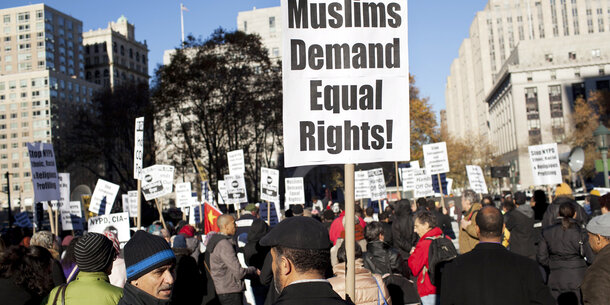 a protestor holds a sign that reads "Muslims demand equal rights!"