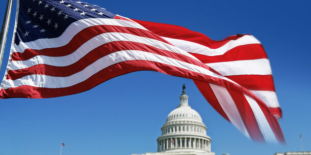 The United States flag flying in front of the Capitol building.