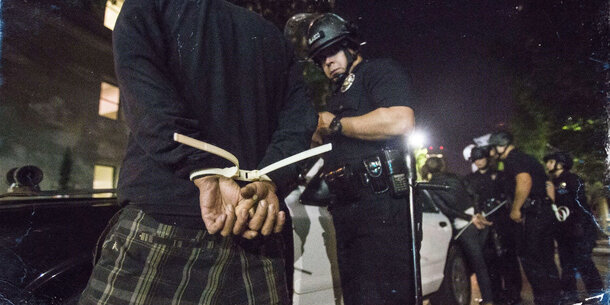 Person restrained by police officers with zip ties