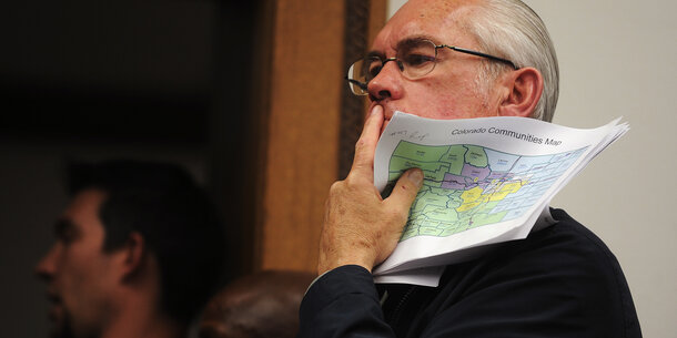 Legislator looks pensive while holding Colorado communities map