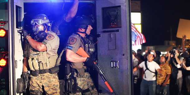 Heavily armed officers with military equipment exit a truck