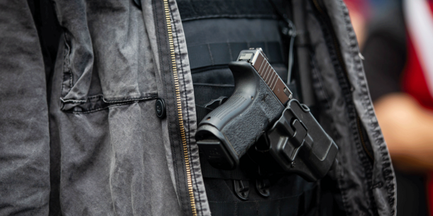 Close-up view of gun strapped to man's chest within jacket
