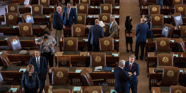 State legislators intermingle around a legislative chamber
