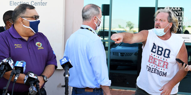 A man yells at an election official in front of press outside the Clark County Election Center