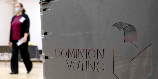 Woman walks past a Dominion Voting machine