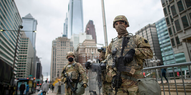 Two National Guard soldiers stand guard in an urban setting