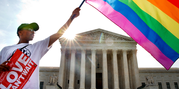 Person waving pride flag in front of Supreme Court