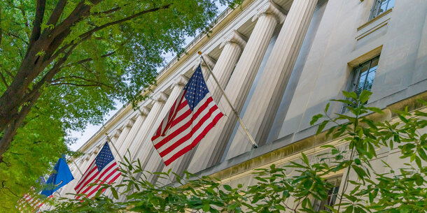facade of the department of justice with American flags