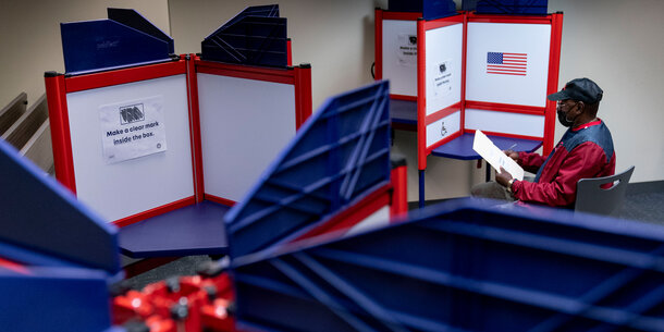 Man filling out voting ballot behind divider