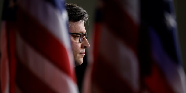House Speaker Mike Johnson behind U.S. flag