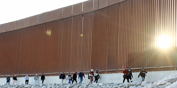 People walking at the US-Mexico border wall