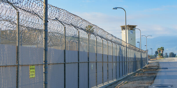 barbed wire fence with guard tower in background