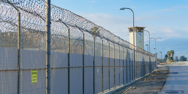 barbed wire fence with guard tower in background