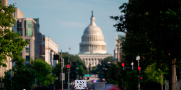 Capitol building in background and "Black Lives Matter" sign held up in the foreground